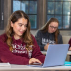 Students working on laptops gather together